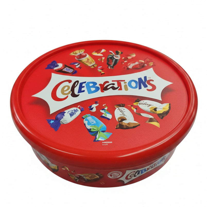 Red 'Celebrations' candy tin with colorful graphics on a black surface