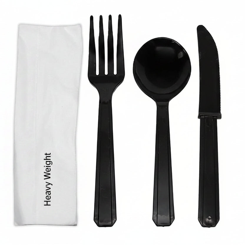 Black plastic fork, spoon, and knife set with a white napkin on a white background