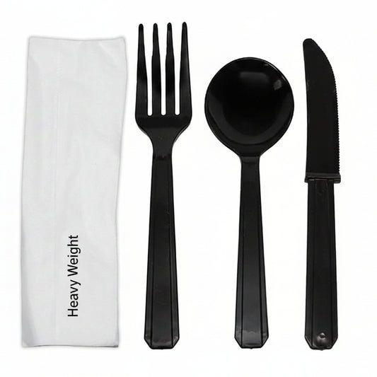 Black plastic fork, spoon, and knife set with a white napkin on a white background
