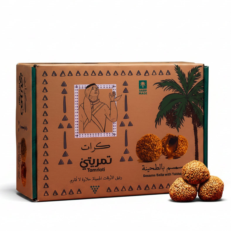 Cardboard box with palm tree design and three round golden candies on a red surface.