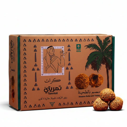Cardboard box with palm tree design and three round golden candies on a red surface.