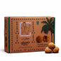 Cardboard box with palm tree design and three round golden candies on a red surface.