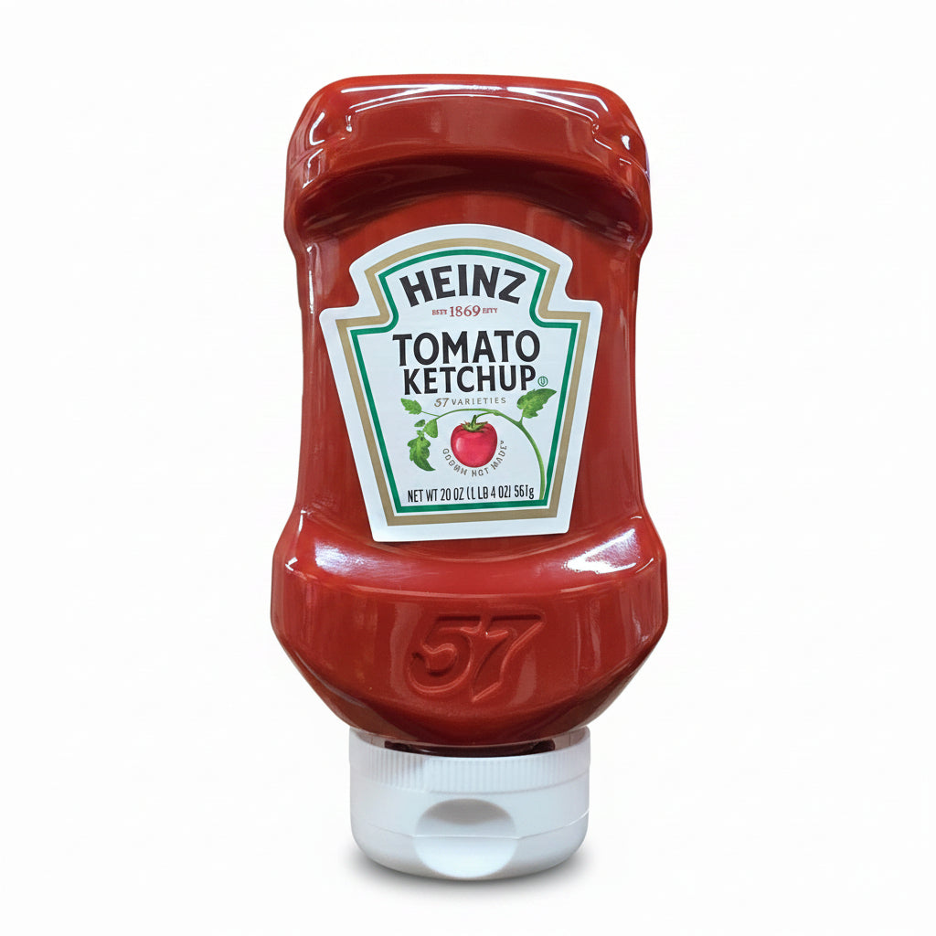 A bottle of Heinz Tomato Ketchup standing on its white cap on an orange store shelf, with warehouse shelves and other products visible in the background.