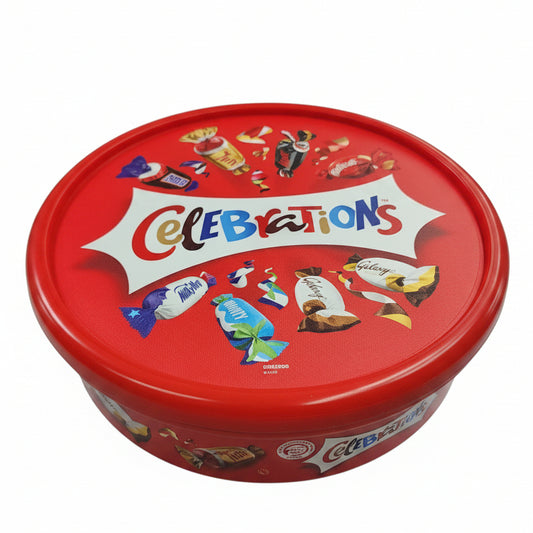 Red 'Celebrations' candy tin with colorful graphics on a black surface